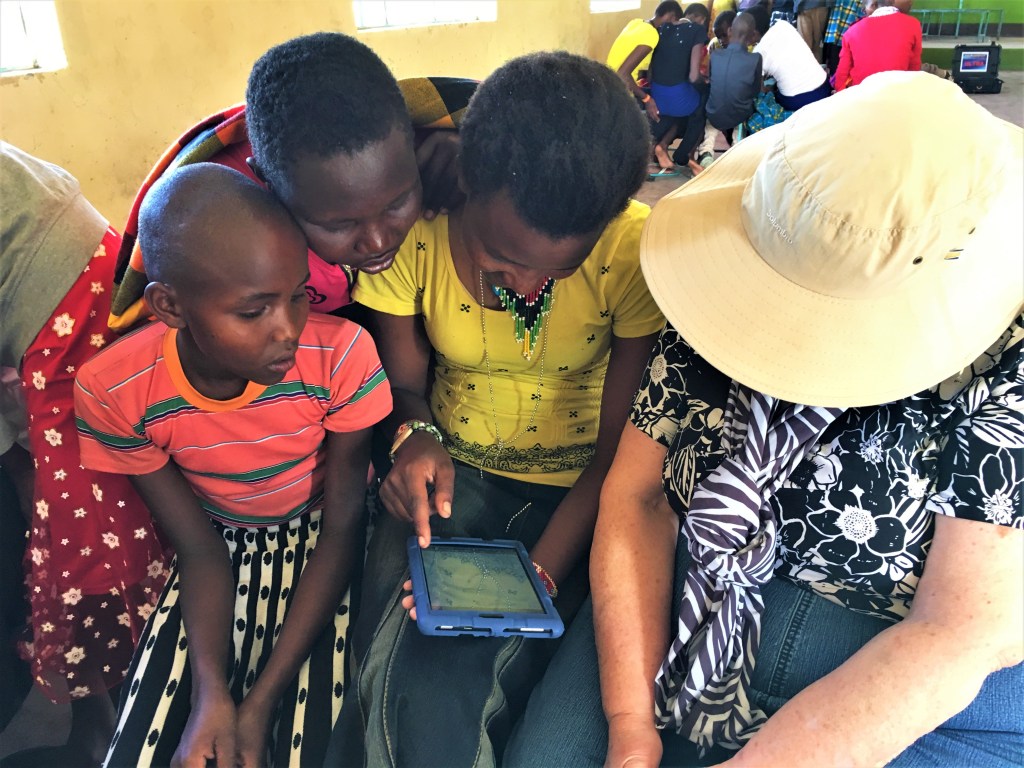 Children in Maasai Mara, Kenya read from an EmpowerReader tablet
