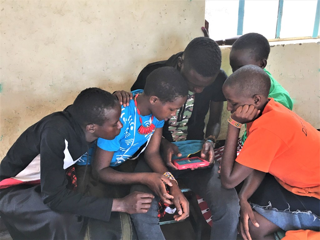 Children in Maasai Mara, Kenya read from an EmpowerReader tablet