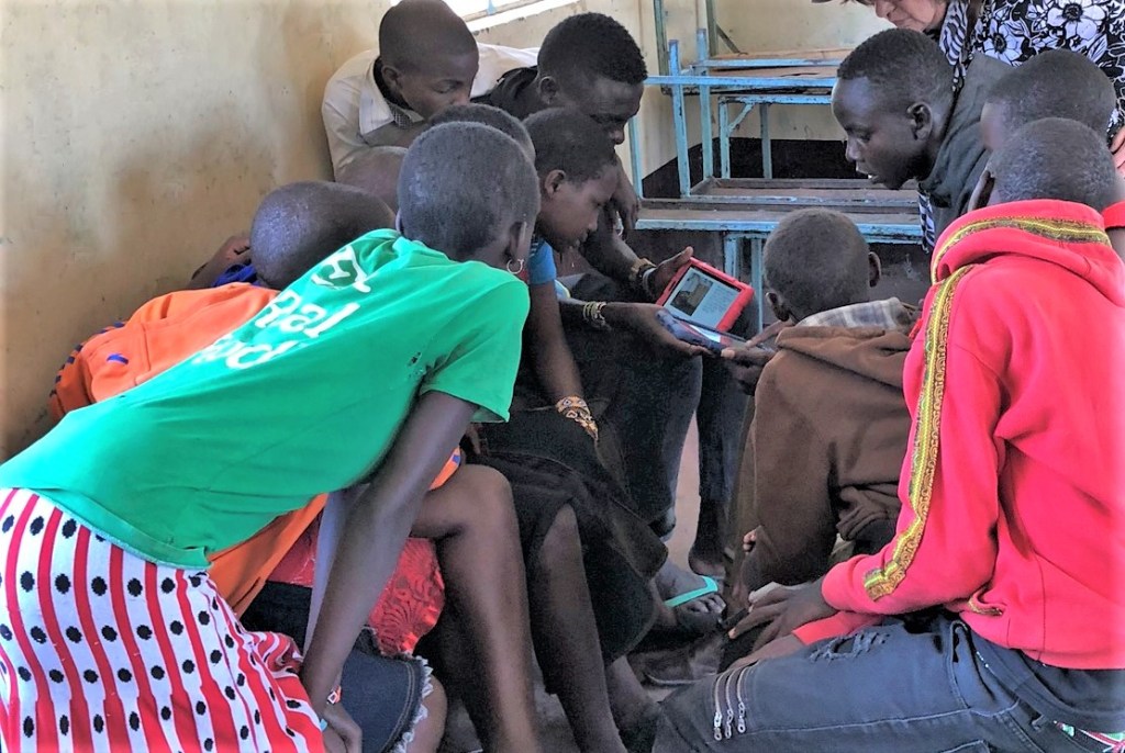 Children in Maasai Mara, Kenya read from an EmpowerReader tablet